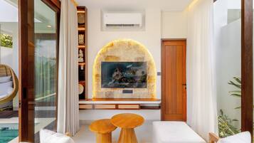 A modern hotel lobby with a stone fireplace, a large framed picture, and a seating area with two wooden tables.
