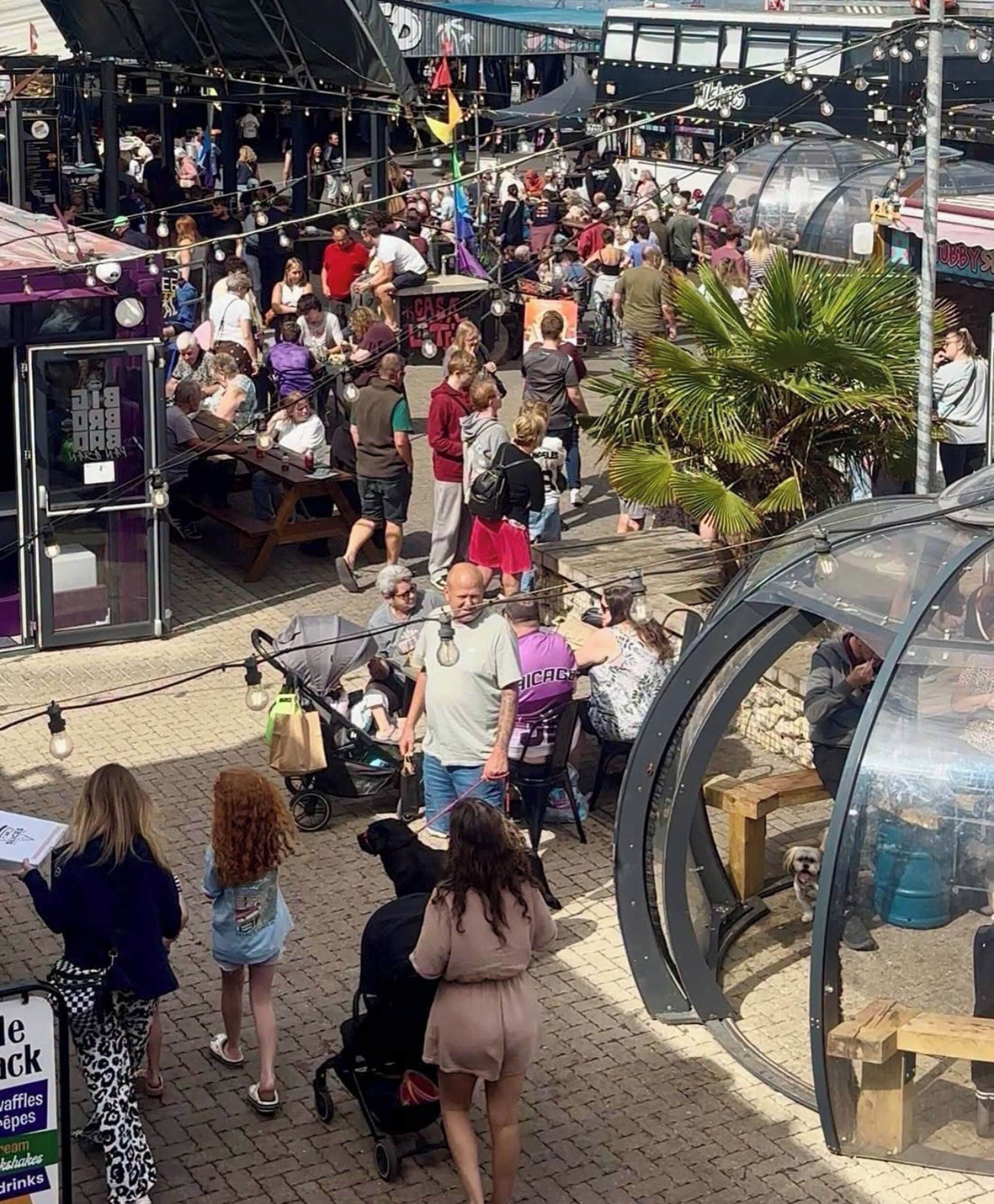 A crowded outdoor market with various stalls and people.