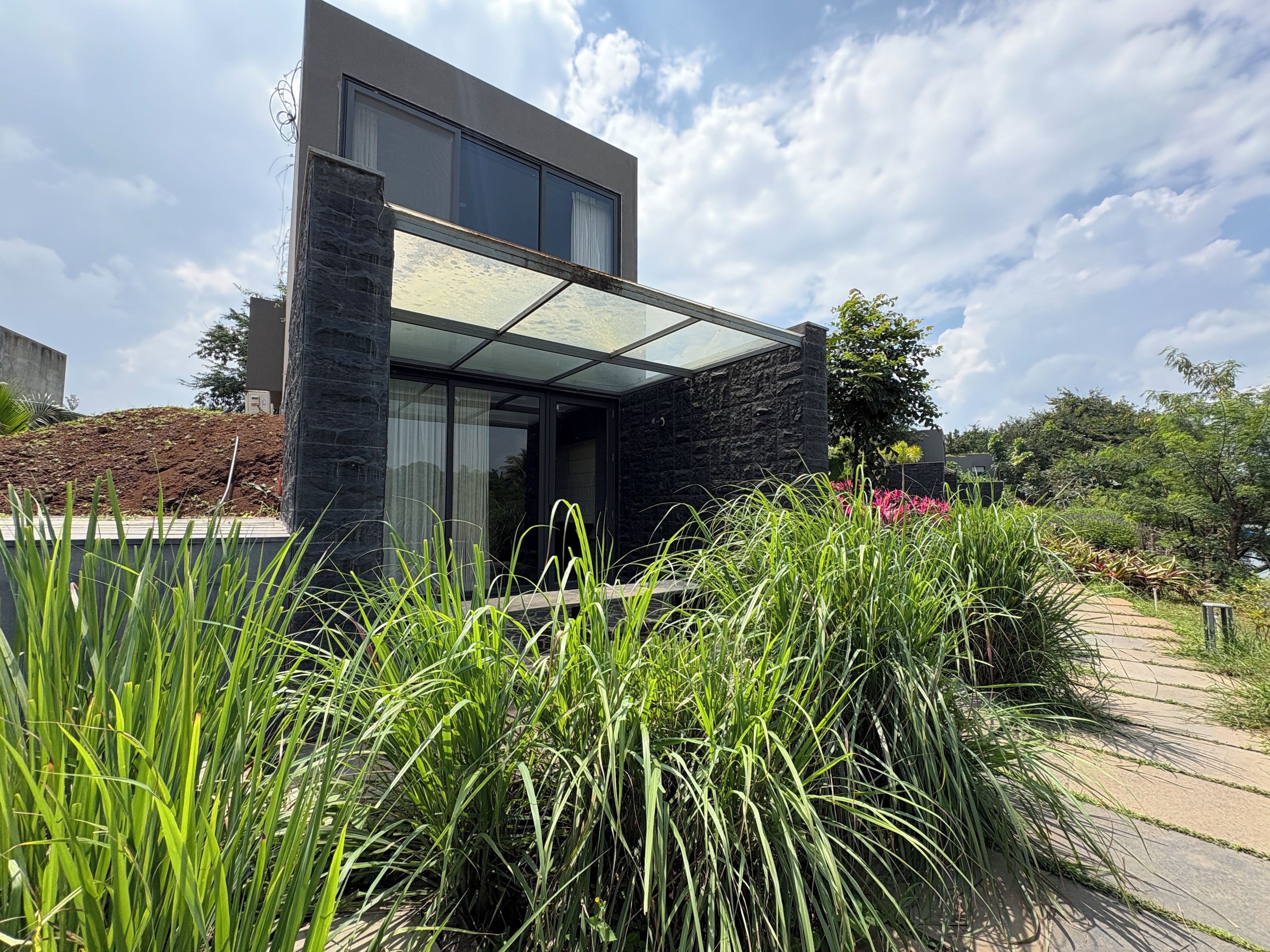 A modern building with a glass facade, stone exterior, and a landscaped garden with tall grasses.