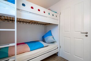 Una cama litera con una cama inferior y una puerta a la derecha.