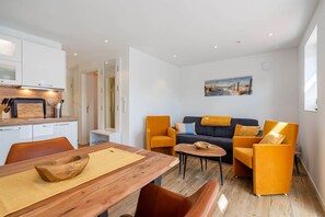 A modern living space with a dining area, sofa set, and kitchen. - Baltrum Vacation Rental (Norden)