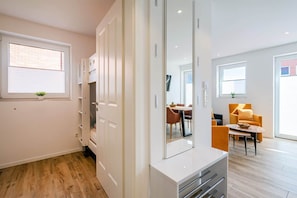 A modern apartment with a dining area, a sofa, and a large mirror. - Baltrum Vacation Rental (Norden)