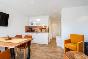 A modern kitchen with white cabinets, a wooden countertop, and a dining area with a wooden table and chairs. - Baltrum Vacation Rental (Norden)