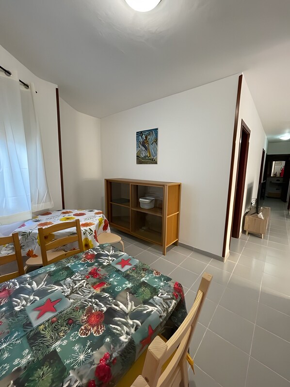 Una stanza con un letto, un armadio in legno, un tavolo da pranzo con sedie e un quadro appeso al muro.
