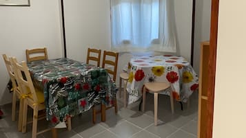 Ruokailutila, jossa on pöytä ja tuolit, ikkuna, jossa on verhot, ja ovi.