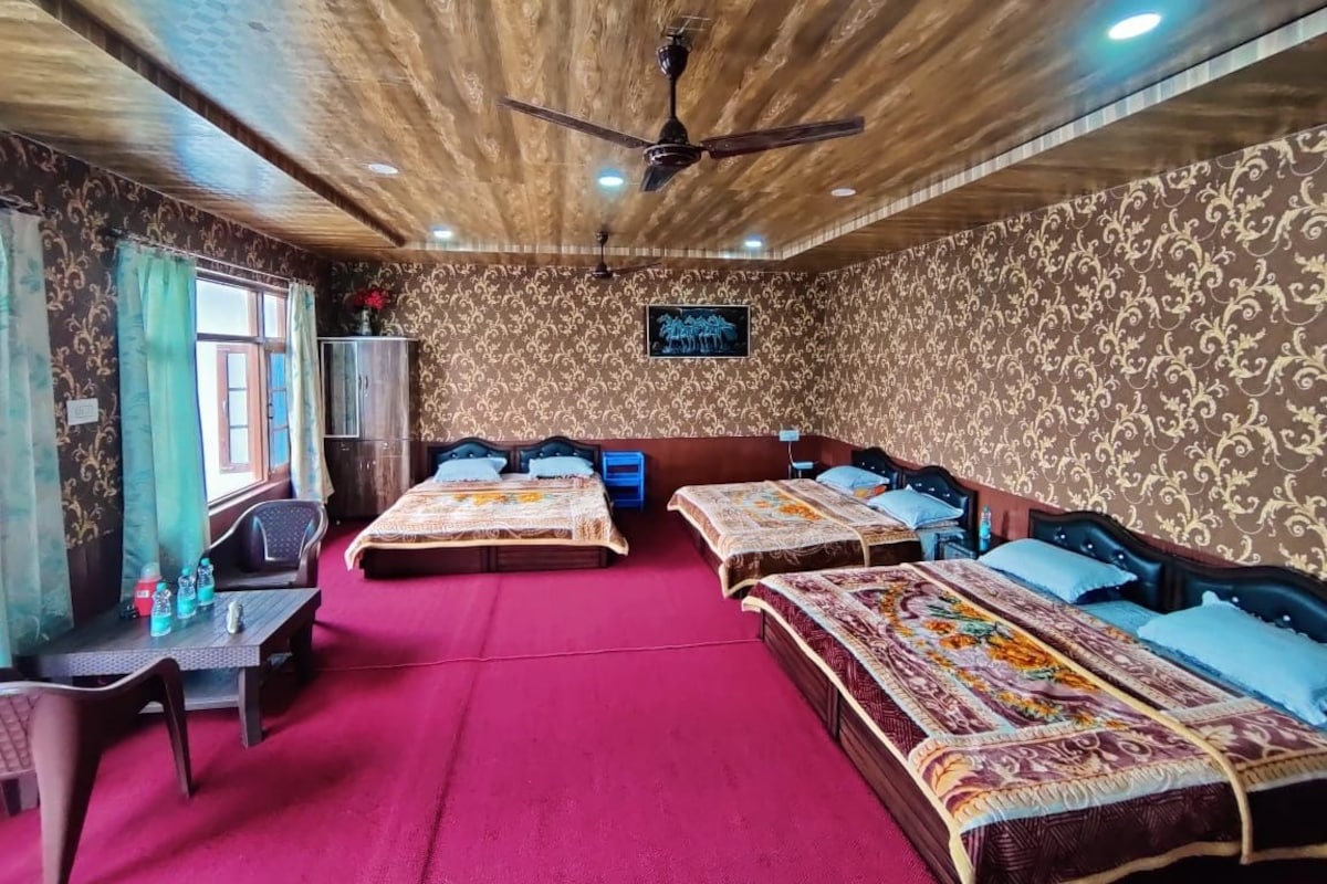 A room with three beds, a desk, and a ceiling fan.