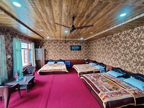 A room with three beds, a desk, and a ceiling fan. - KASHMIR HOMESTAY (Baramula)