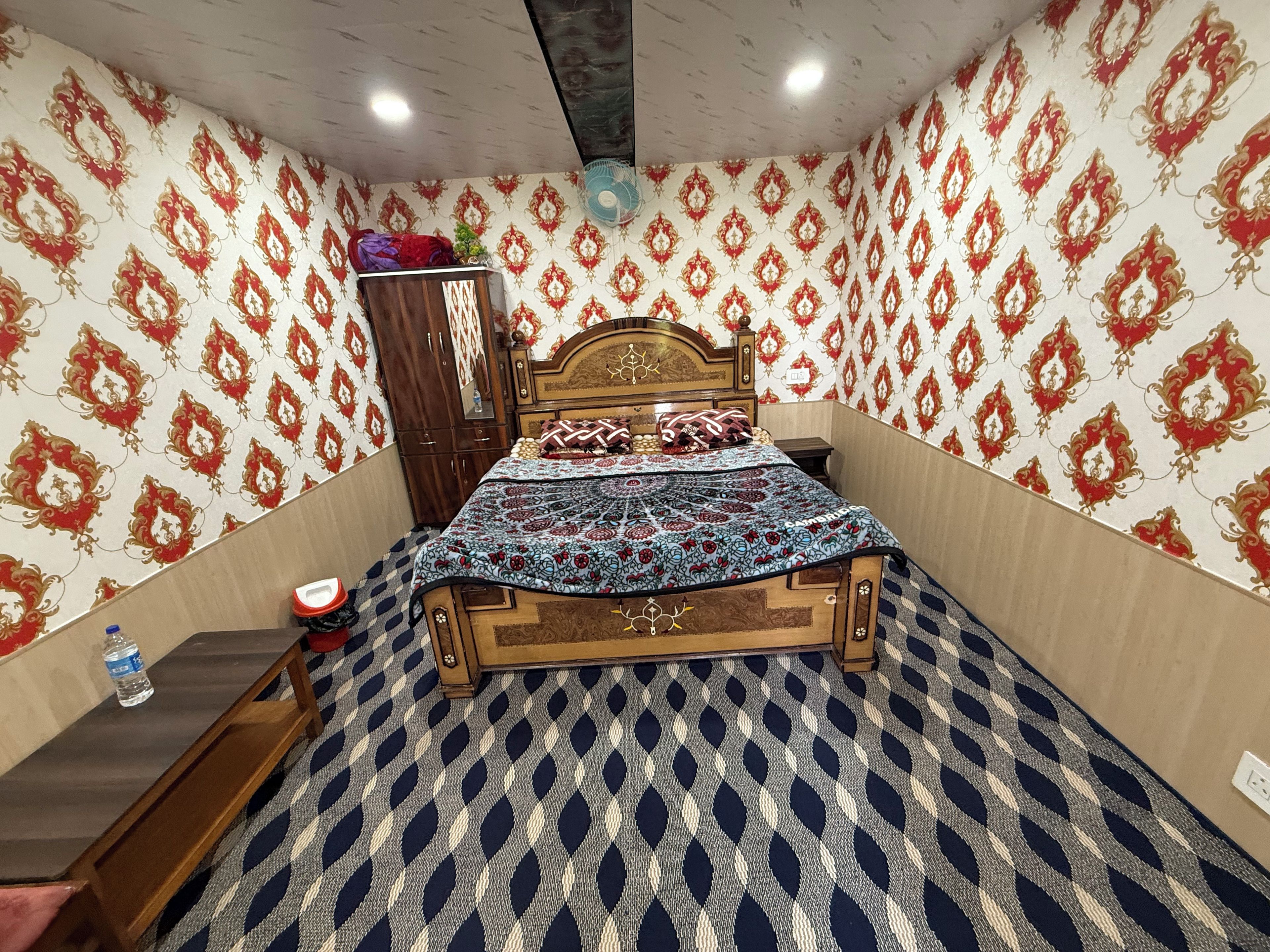 Un dormitorio con alfombra estampada, una cama de madera y un armario.