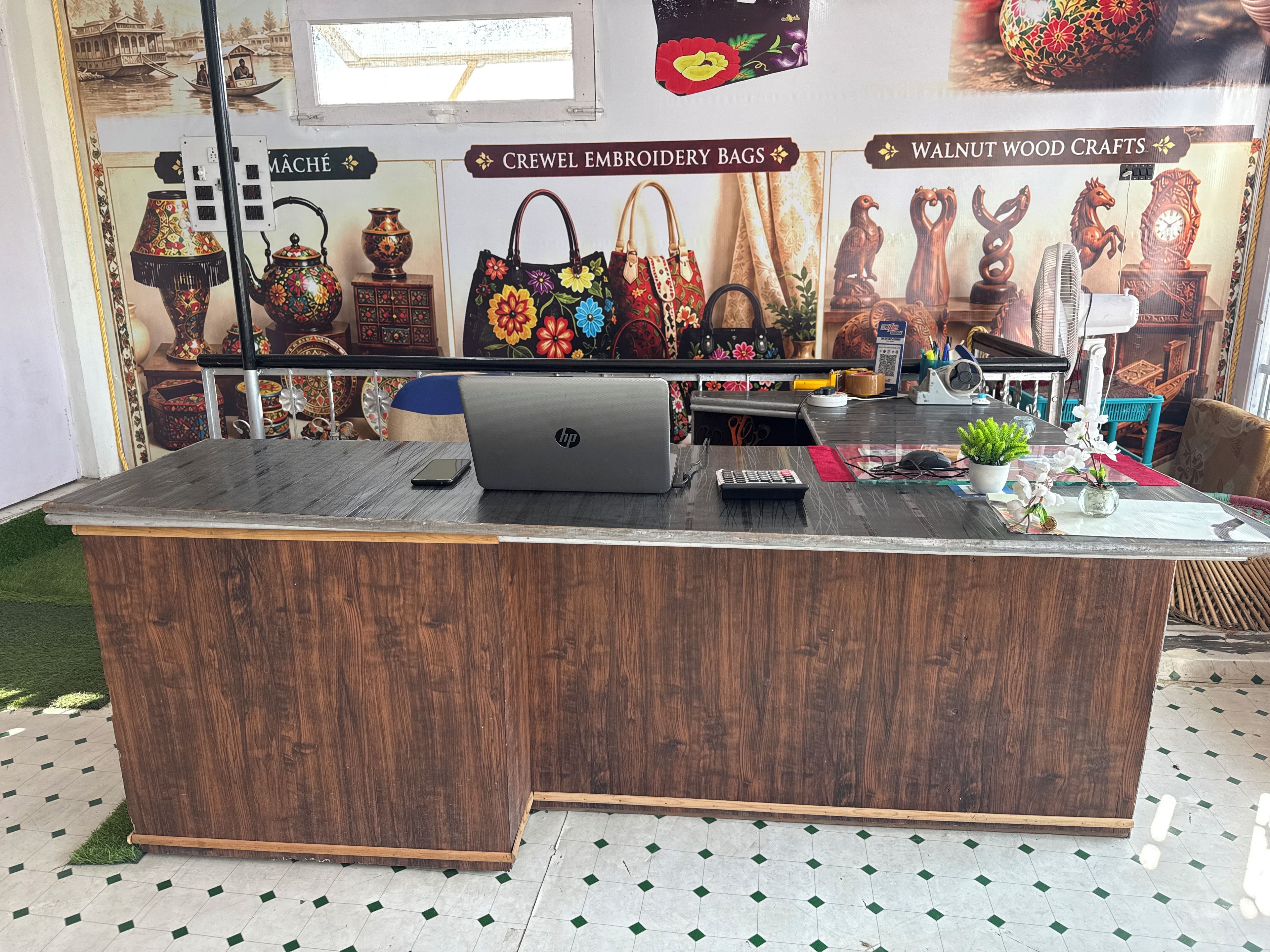 Un mostrador de recepción de madera con una computadora portátil, una calculadora y un teléfono celular.