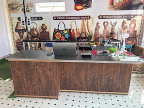 A wooden reception desk with a laptop, a calculator, and a mobile phone. - KASHMIR HOMESTAY (Baramula)