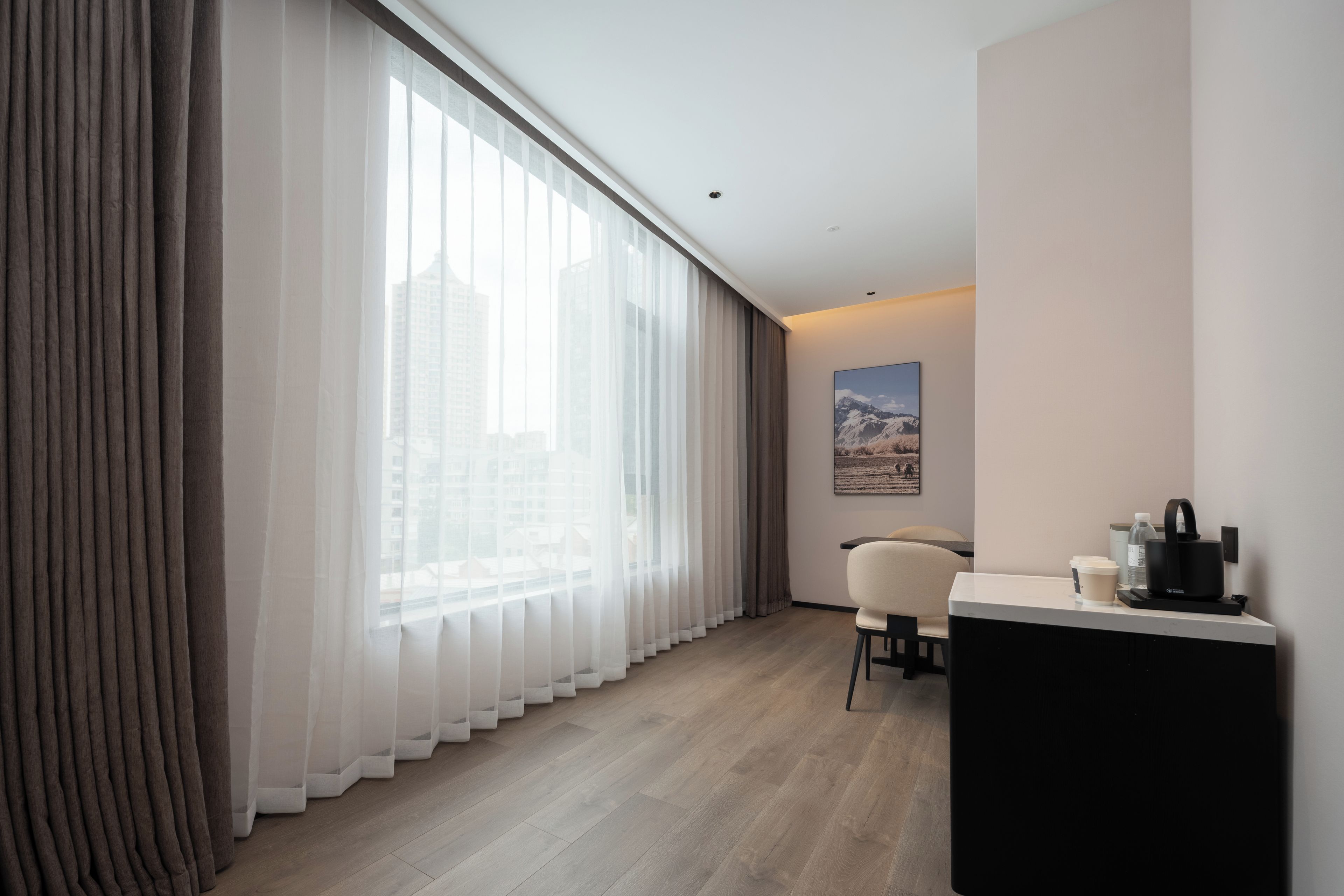 A modern hotel room with a large window, a desk, and a chair.