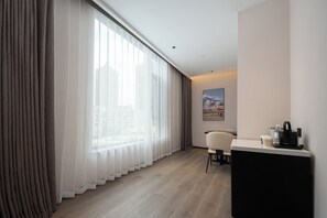 Una habitación de hotel moderna con un ventanal grande, un escritorio y una silla.