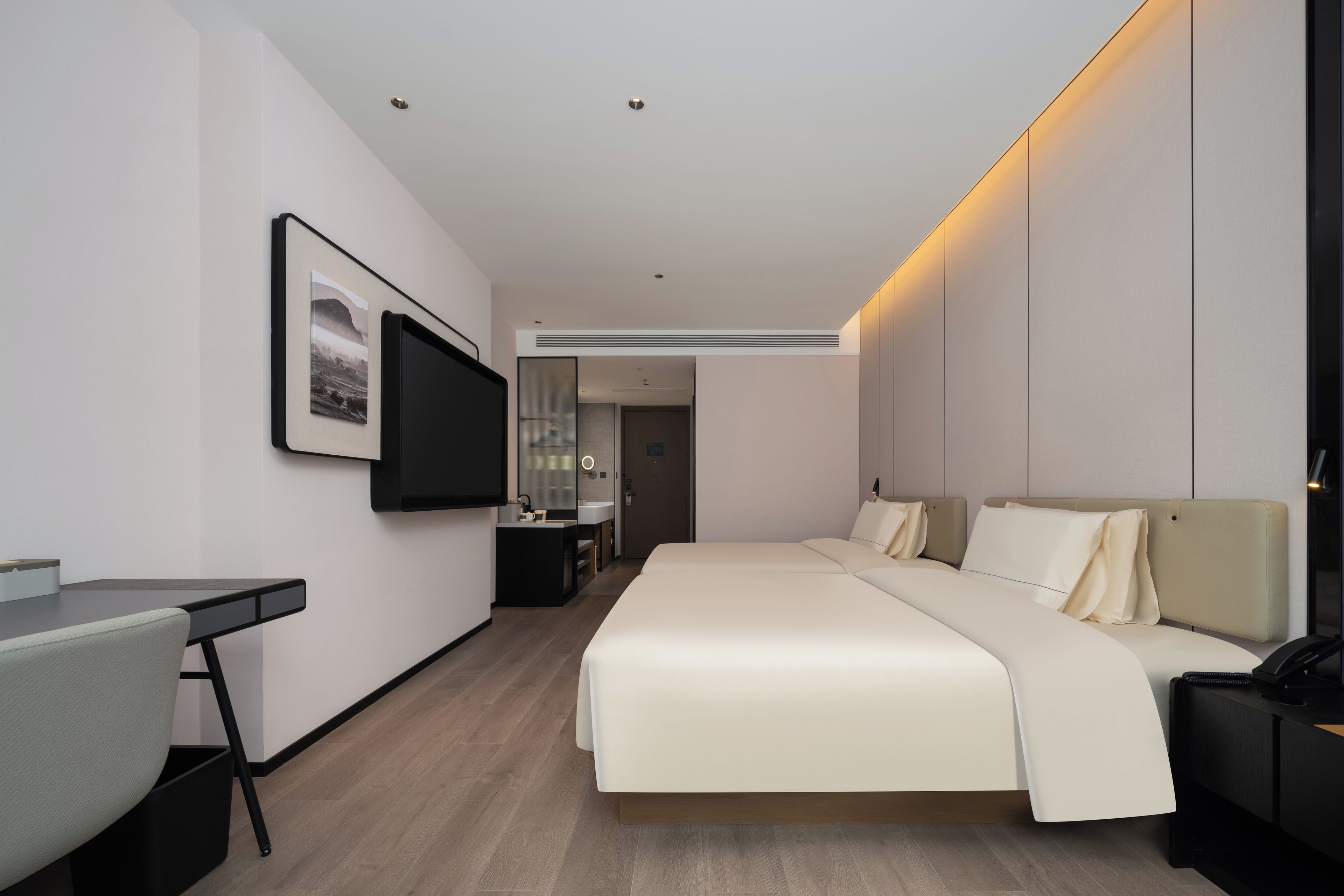 Una habitación de hotel moderna con cama, escritorio y televisor de pantalla plana montado en la pared.