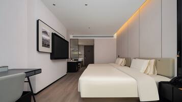 Una habitación de hotel moderna con cama, escritorio y televisor de pantalla plana montado en la pared.