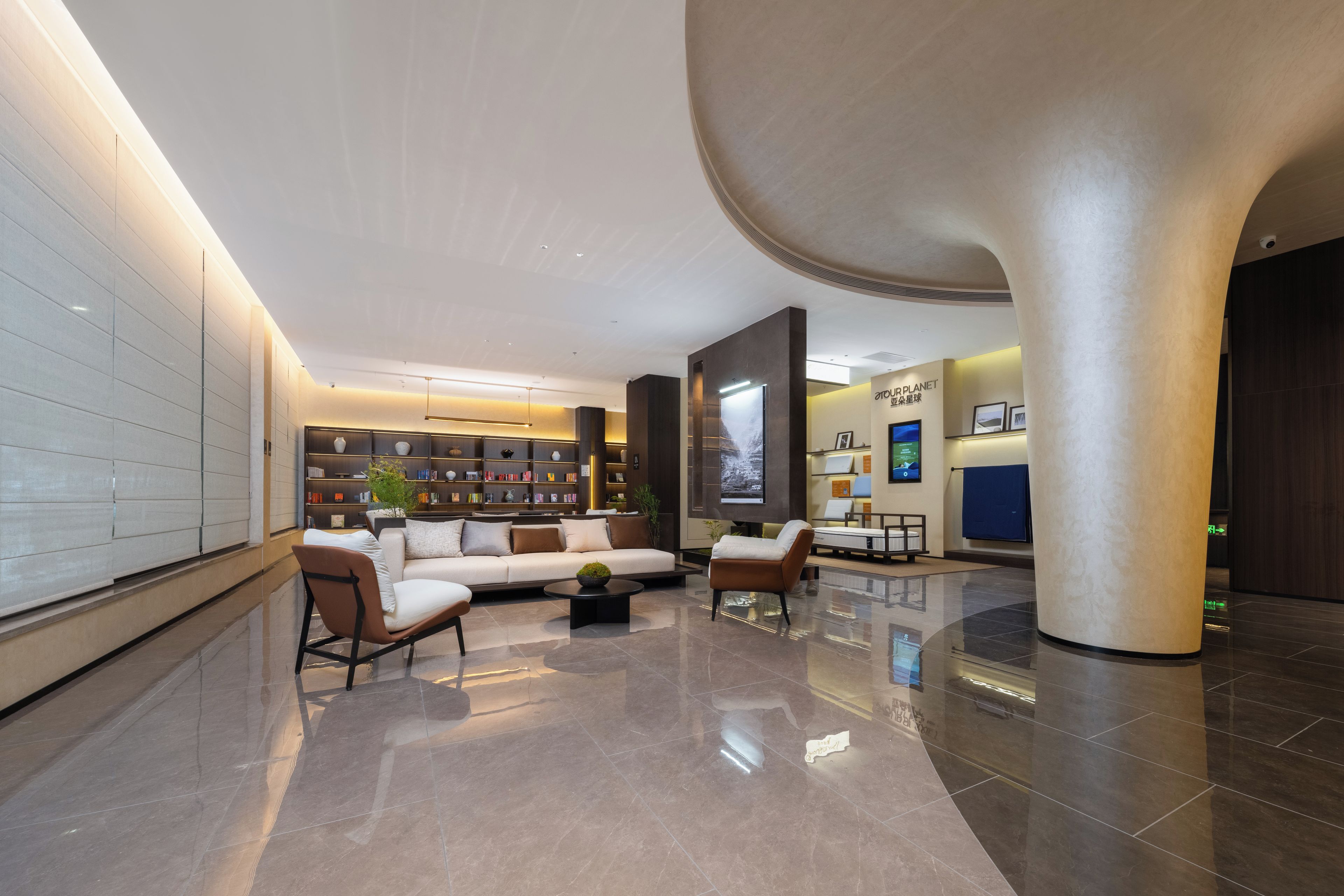 A spacious lobby with a modern sofa, a coffee table, and a bookshelf filled with books.