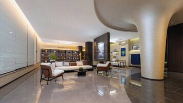 A spacious lobby with a modern sofa, a coffee table, and a bookshelf filled with books.