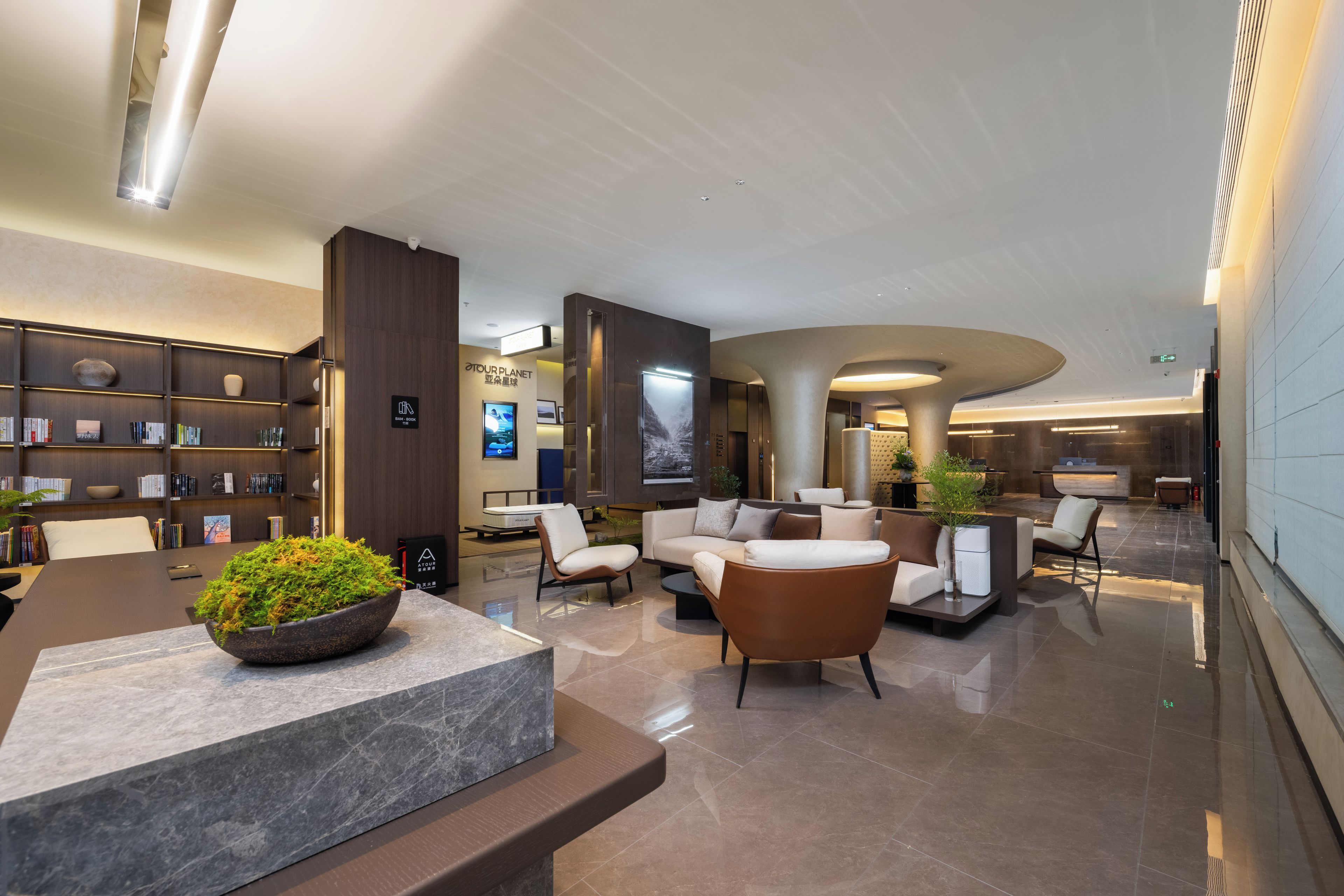 A modern lobby with a reception desk, seating area, and a bookshelf.