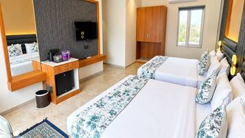 Habitación de hotel con una cama grande, televisión, armario, escritorio con computadora y ventana.