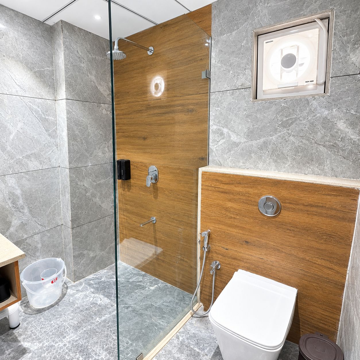 A modern bathroom with a glass-enclosed shower, a wooden vanity, and a toilet.
