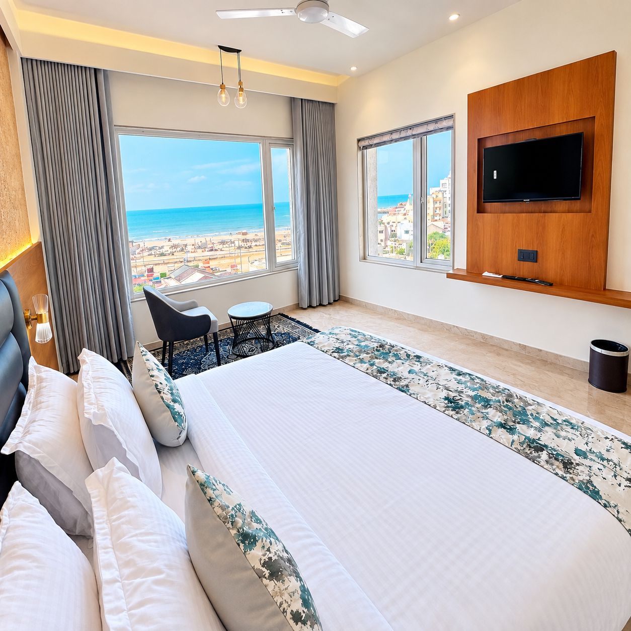 Habitación de hotel con una cama grande, un televisor en la pared, una mesita y vistas a la playa.