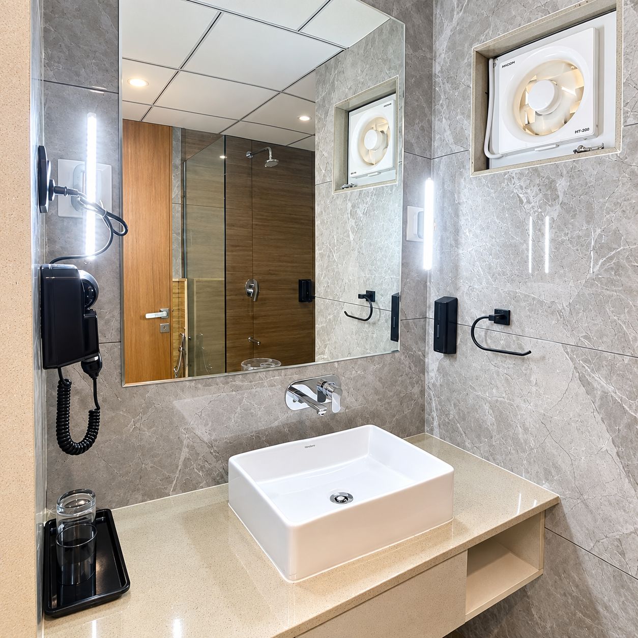 Un baño moderno con un espejo grande, un lavabo, un secador de pelo y un calefactor empotrado.