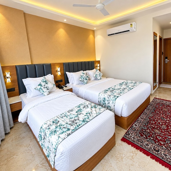 A hotel room with two beds, a ceiling fan, an air conditioning unit, and a red carpet. - Hotel Dwarka Palace (Dwarka)