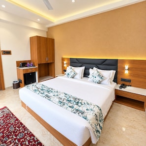 Una habitación de hotel moderna con una cama grande, una mesita de noche, un armario de madera y un escritorio pequeño con un cubo de basura.