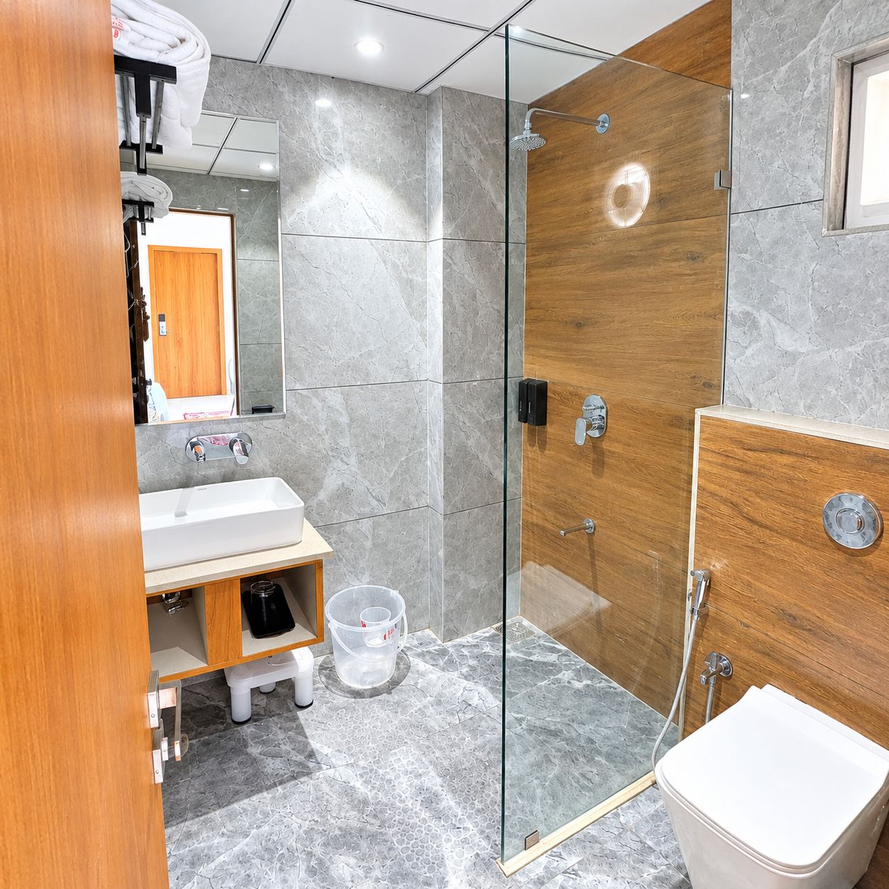 Et stilfuldt badeværelse med en glasafskærmet brusekabine, et træbordplads og et toilet.