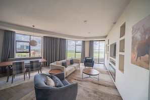 A spacious living room with a large window, a dining area, and a seating arrangement.
