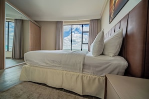 A spacious bedroom with a large bed, a view of the sky through a window, and a modern design. - Rapenda 2bedroom Park View Apartments (Nairobi)