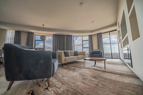 A spacious living room with a large window, a sofa, a chair, and a coffee table.