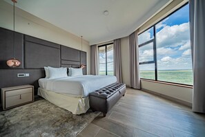 Une chambre à coucher moderne avec un grand lit, une table de chevet, un banc et une vue sur le ciel et le paysage.