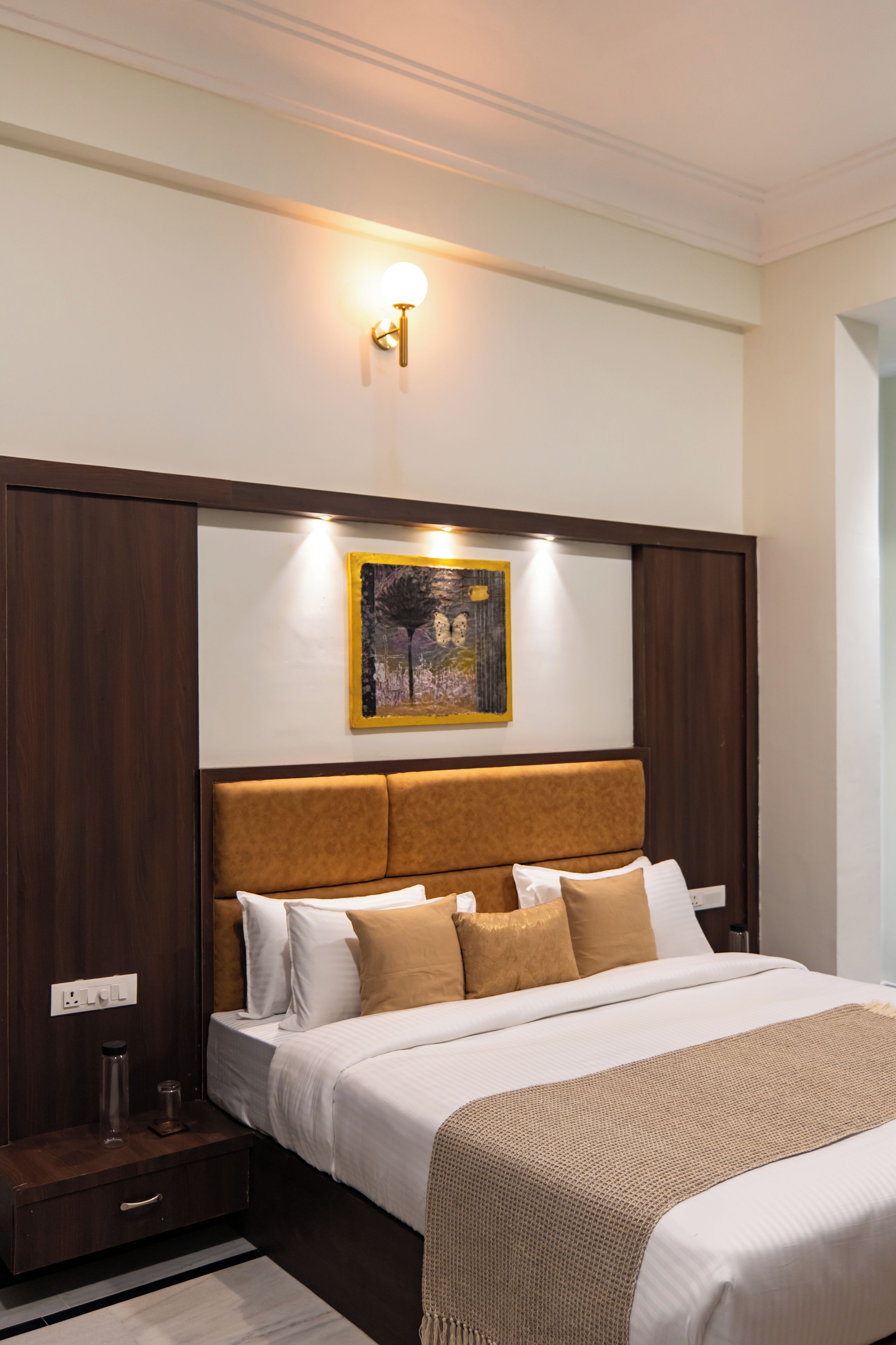 A hotel room with a bed, a nightstand, a lamp, and a painting on the wall.