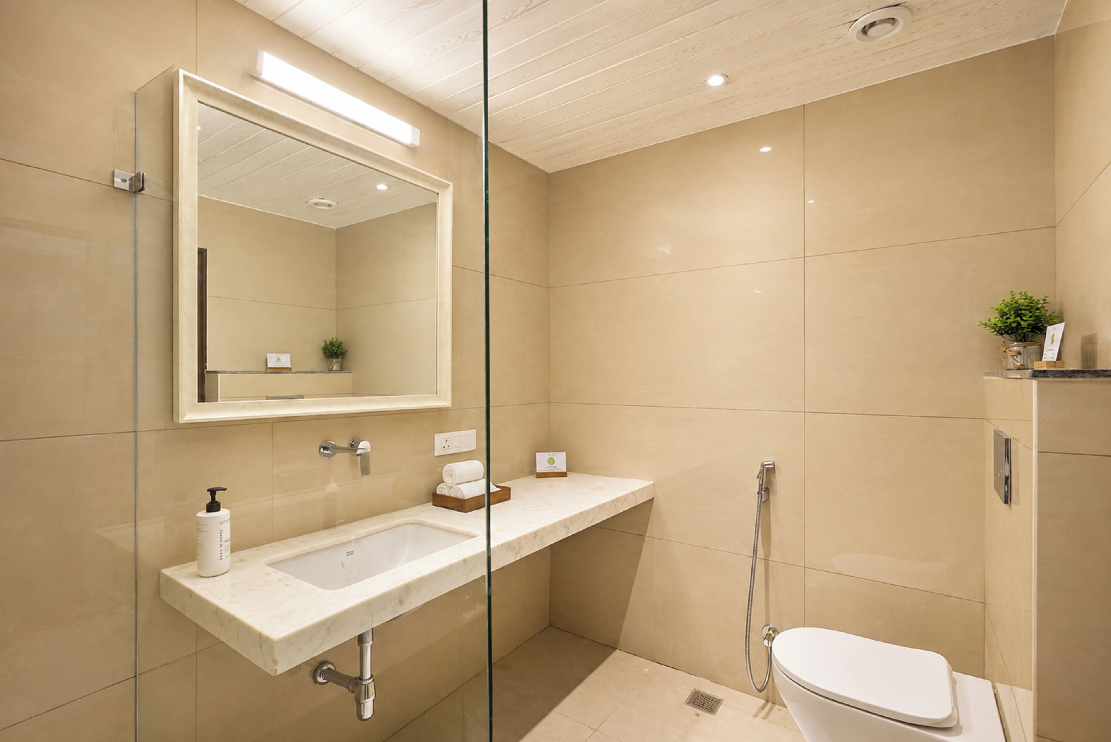 A modern bathroom with a glass partition, a sink, a toilet, and a shower area.
