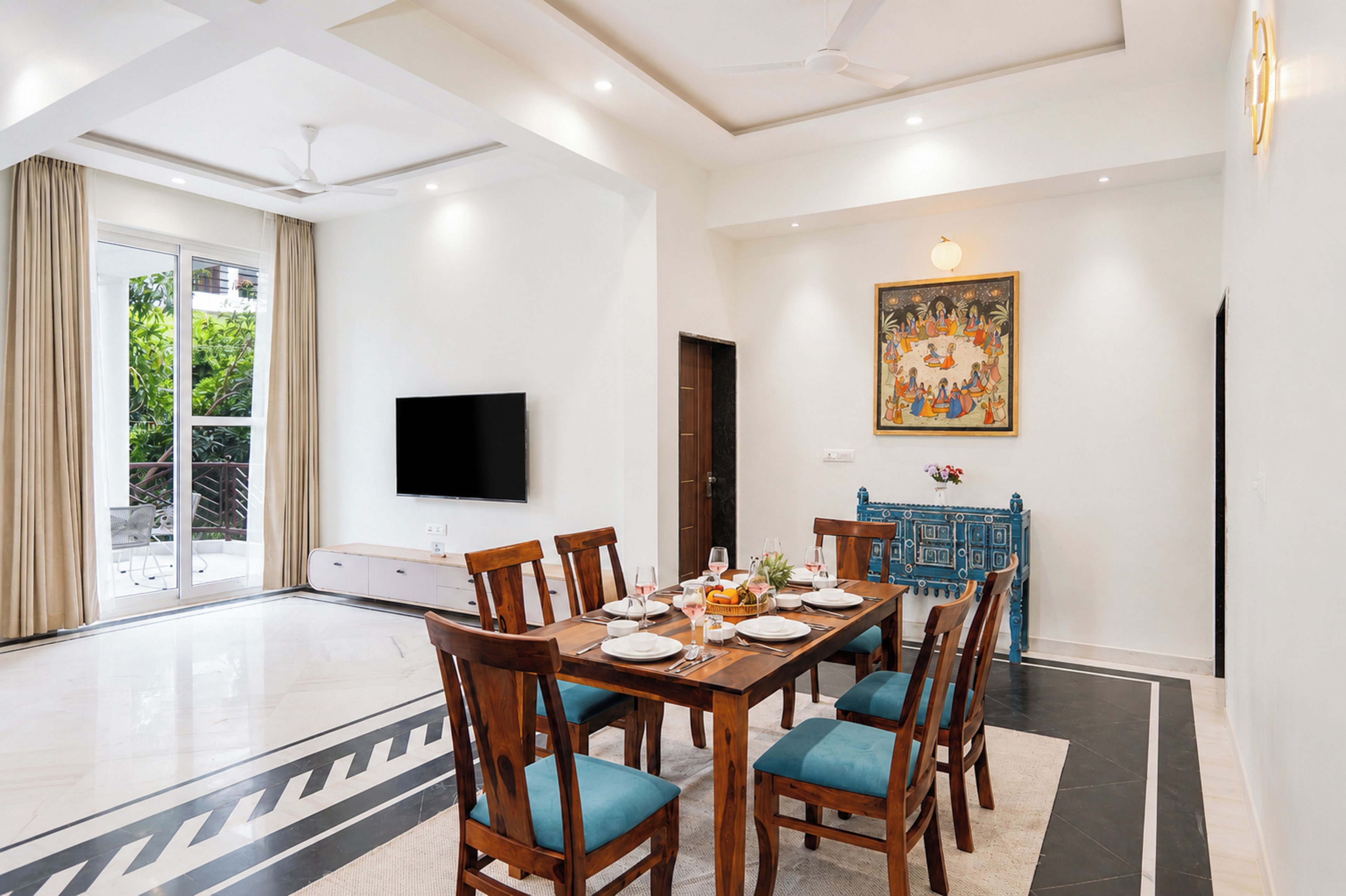 A dining area with a large table, chairs, and a flat-screen TV mounted on the wall.