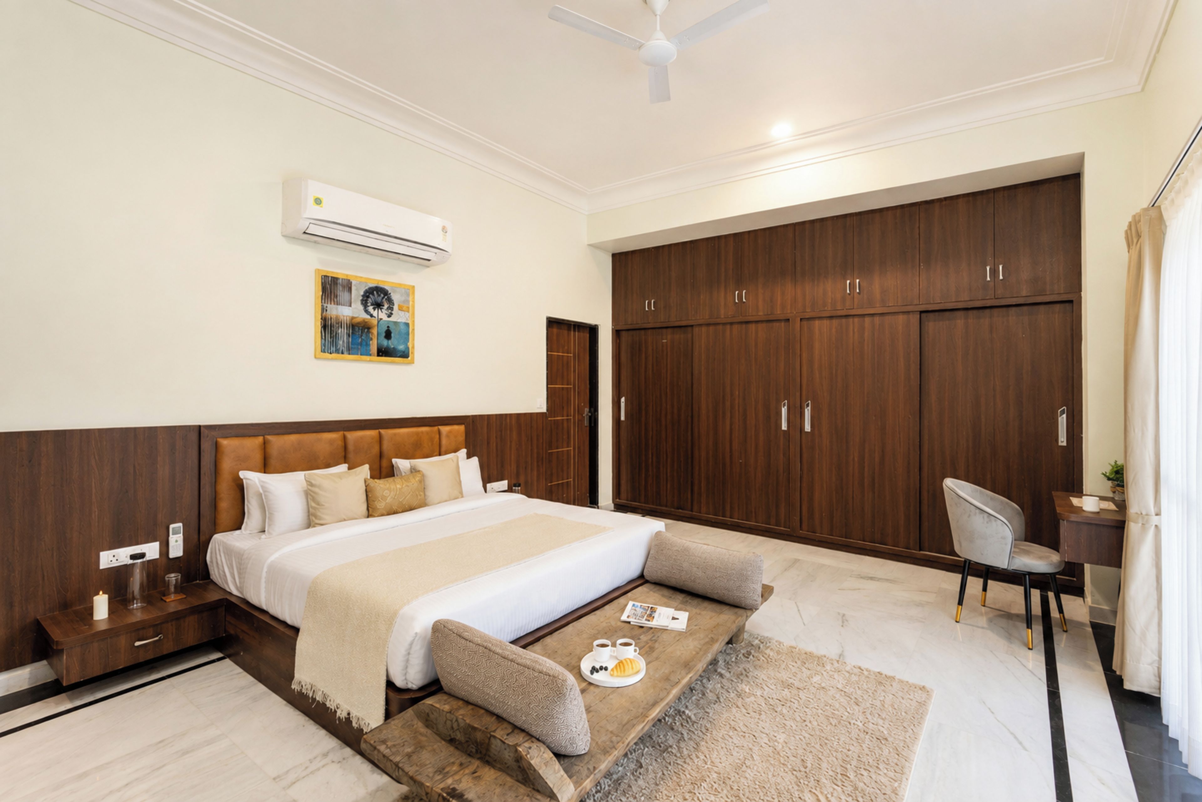 A modern bedroom with a large bed, a wardrobe, a desk, and a ceiling fan.