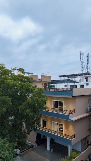 A multi-story residential building with balconies, a water tank on the roof, and a satellite dish. - Alaya Stays Riva Amar Villa 3BHK (Udaipur)