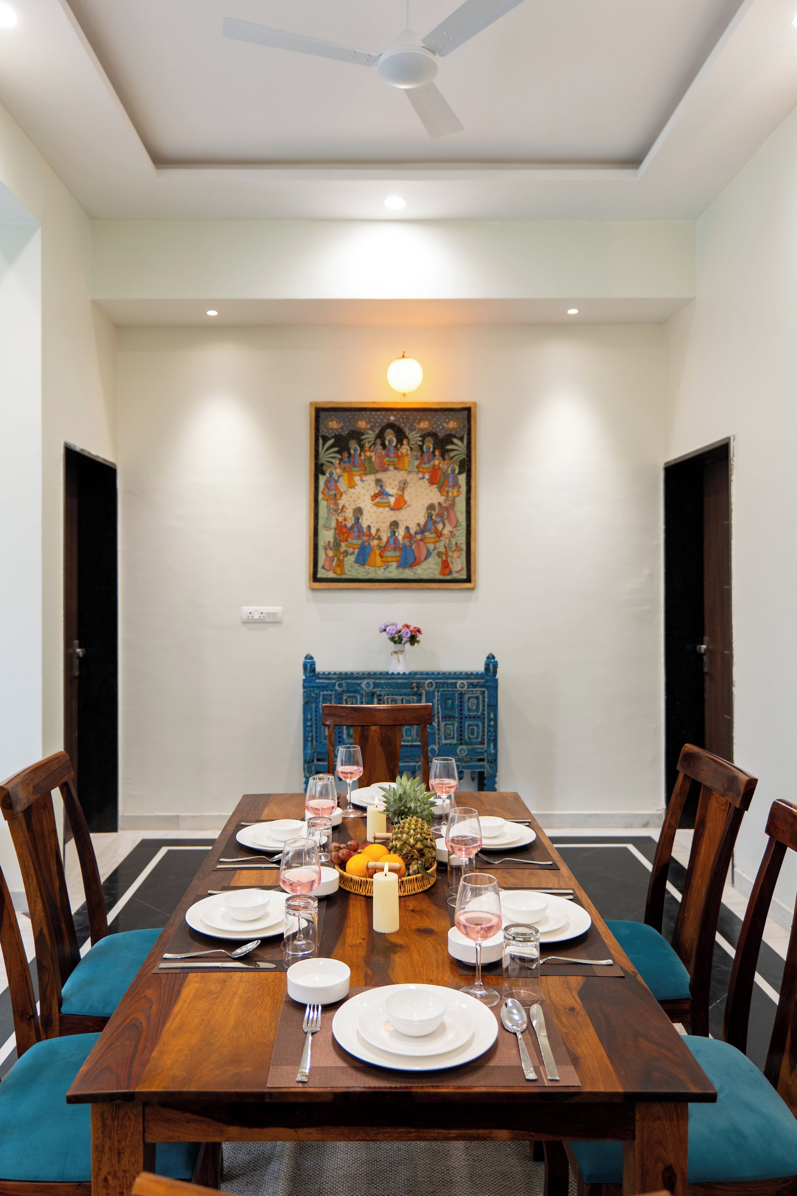 A dining room with a wooden table set for six, chairs, and a ceiling fan.