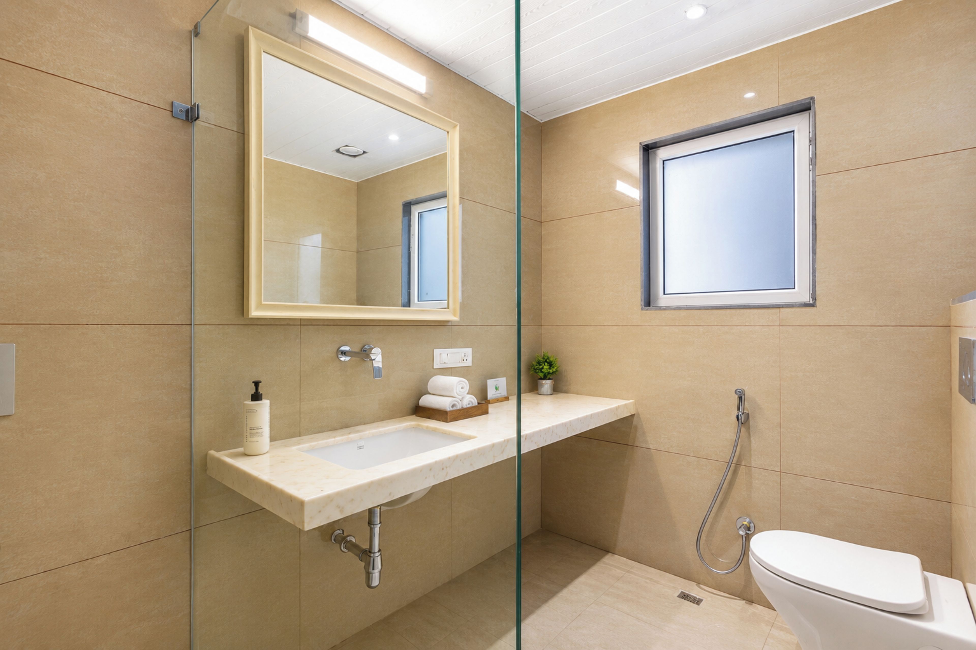 A modern bathroom with a glass partition, a sink, a toilet, and a shower.