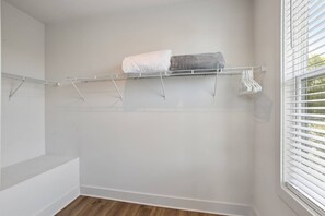 Huoneessa on seinään integroitu hyllykkö, ikkunassa sälekaihtimet ja lattialla puulattia.