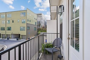 A balcony with a chair and a door, overlooking a street with buildings. - Luxury Townhome with Garage, Walkability a 10 (Atlanta)