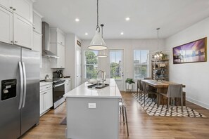 A modern kitchen with a central island, stainless steel appliances, and pendant lighting. - Luxury Townhome with Garage, Walkability a 10 (Atlanta)