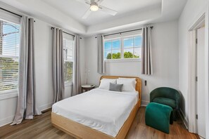 A bedroom with a bed, a chair, a bedside table, and a window with curtains. - Luxury Townhome with Garage, Walkability a 10 (Atlanta)