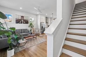A modern living room with a grey sofa, a coffee table, and a large plant. - Luxury Townhome with Garage, Walkability a 10 (Atlanta)