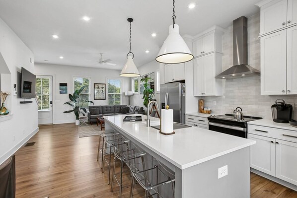 A modern kitchen with white cabinetry, stainless steel appliances, and a central island with bar stools.