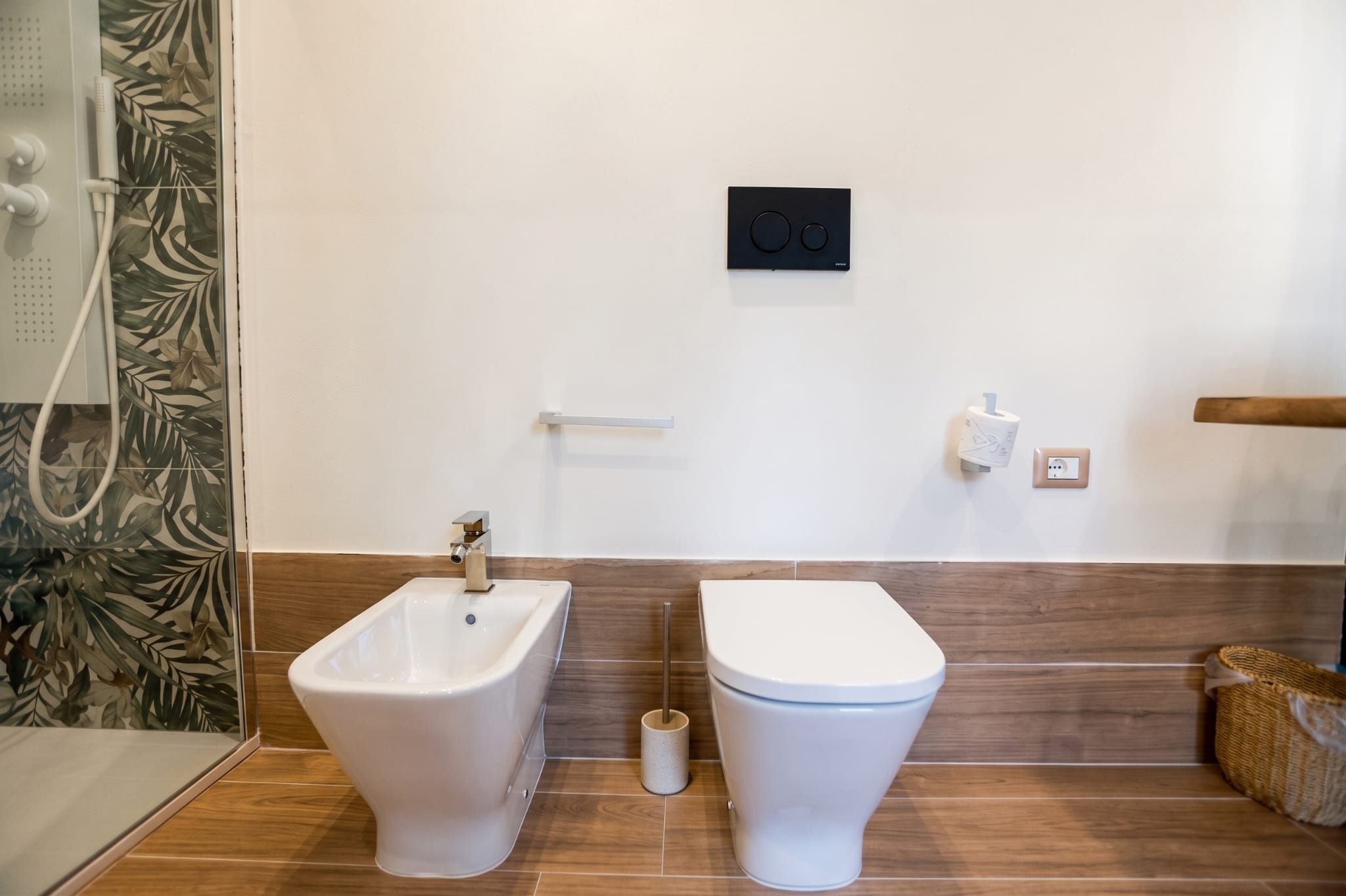A bathroom with a bidet, toilet, and a shower.