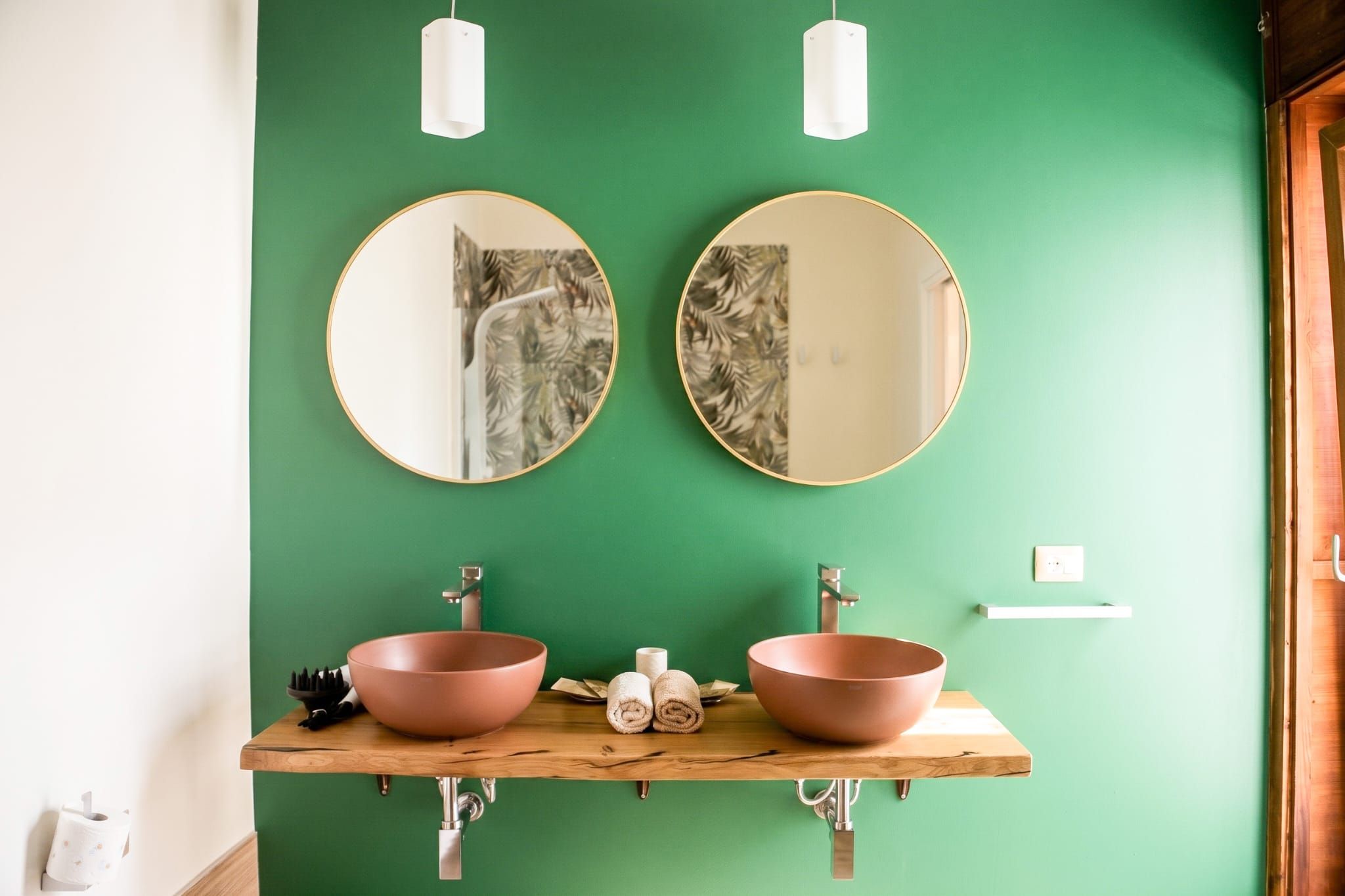 A bathroom with two sinks, two mirrors, and a green wall.