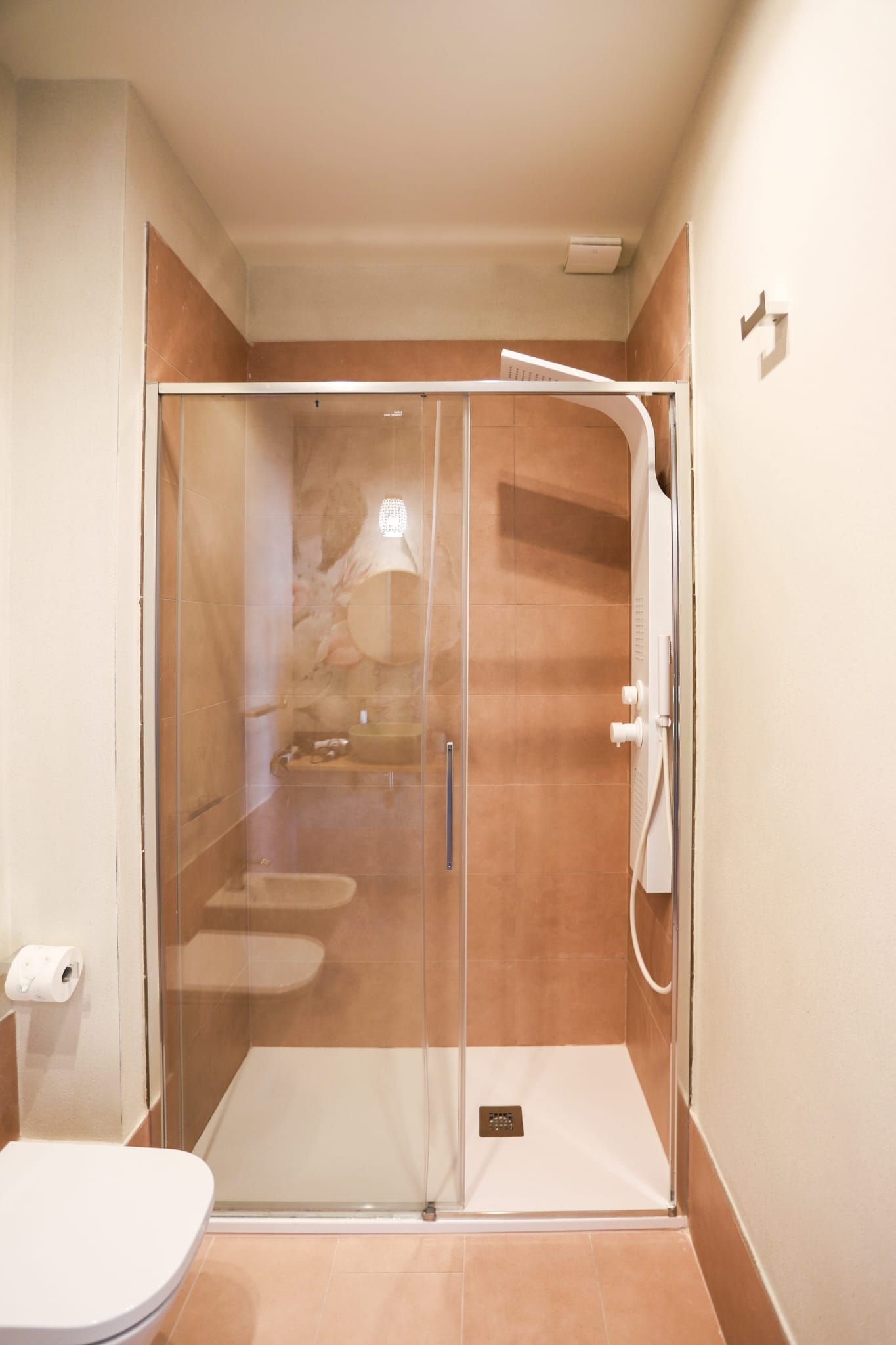 A bathroom with a glass-enclosed shower, a toilet, and a sink.