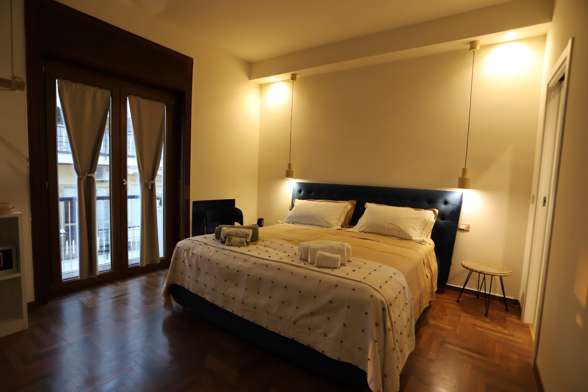 A bedroom with a bed, bedside tables, a chair, and a view through a door.