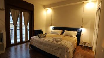 A bedroom with a bed, bedside tables, a chair, and a view through a door.